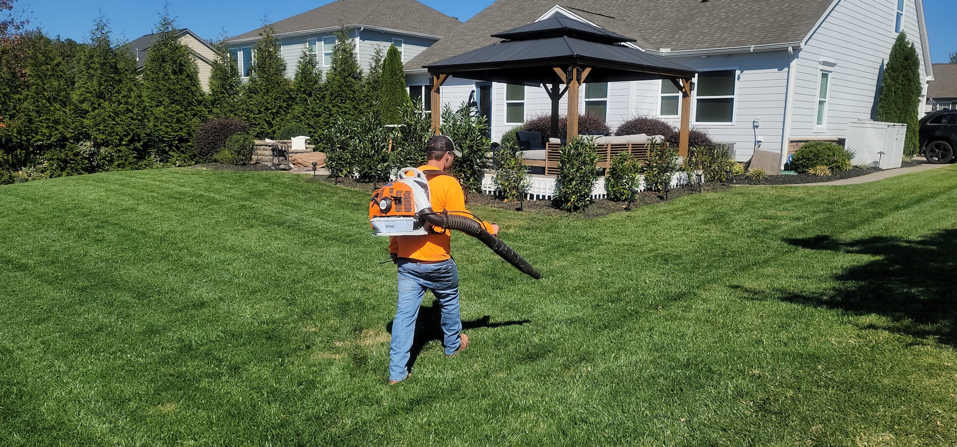 A man in an orange shirt holding a baseball bat